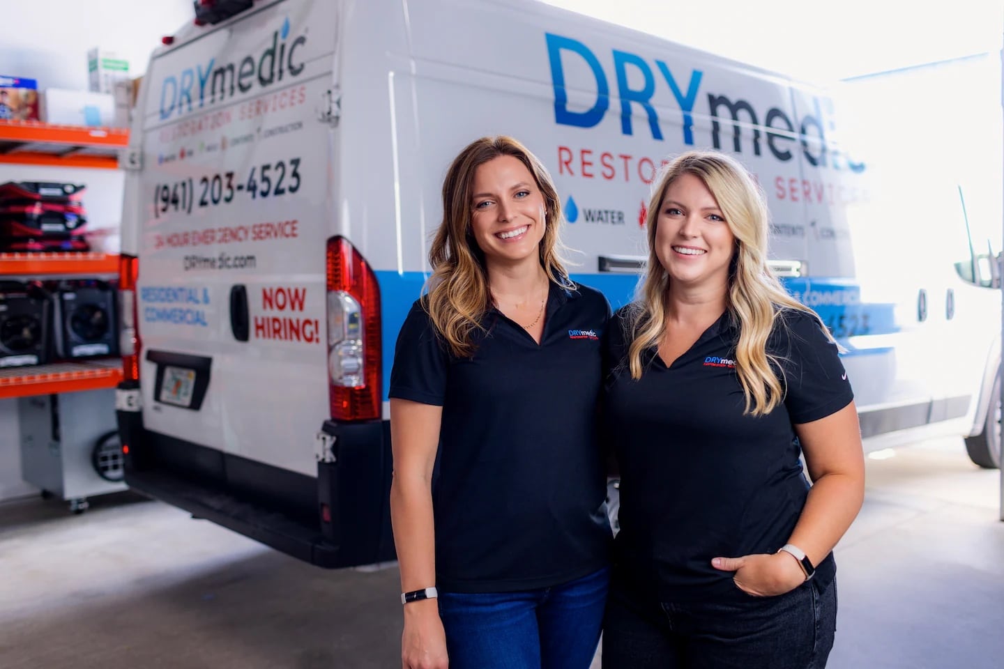 Two DryMedic restoration specialists standing beside a company service van on.