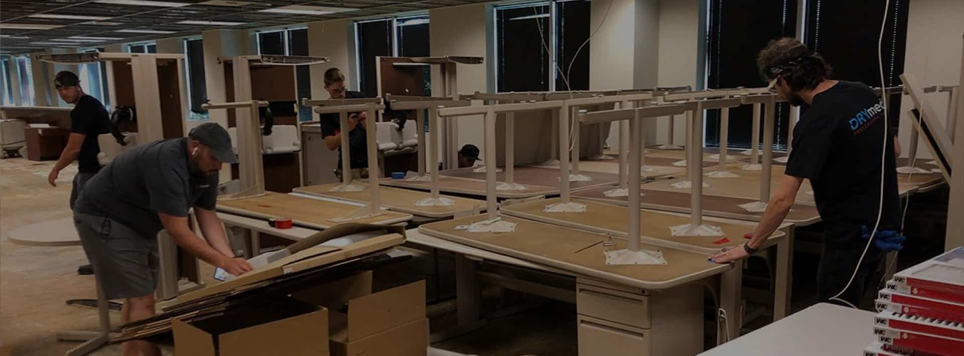 Restoration crew cleaning and repairing furniture in a commercial office space.